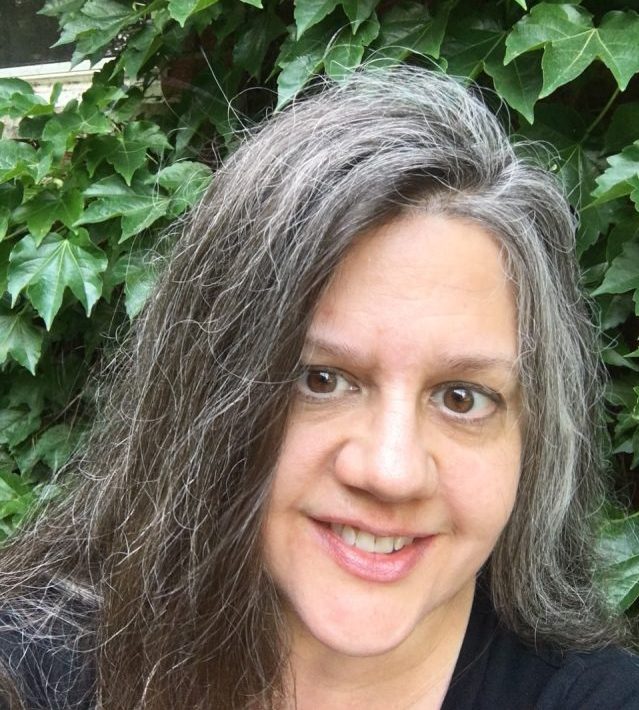 Smiling woman with a black shirt in front of green shrubbery