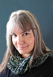 Headshot of speaker Jennifer Lawler with a gray and black scarf and black top on a gray background